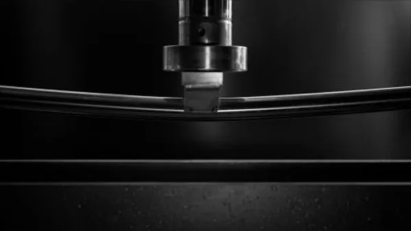 stainless steel mirror polished rounded tubing being stress tested under a hydraulic arm
