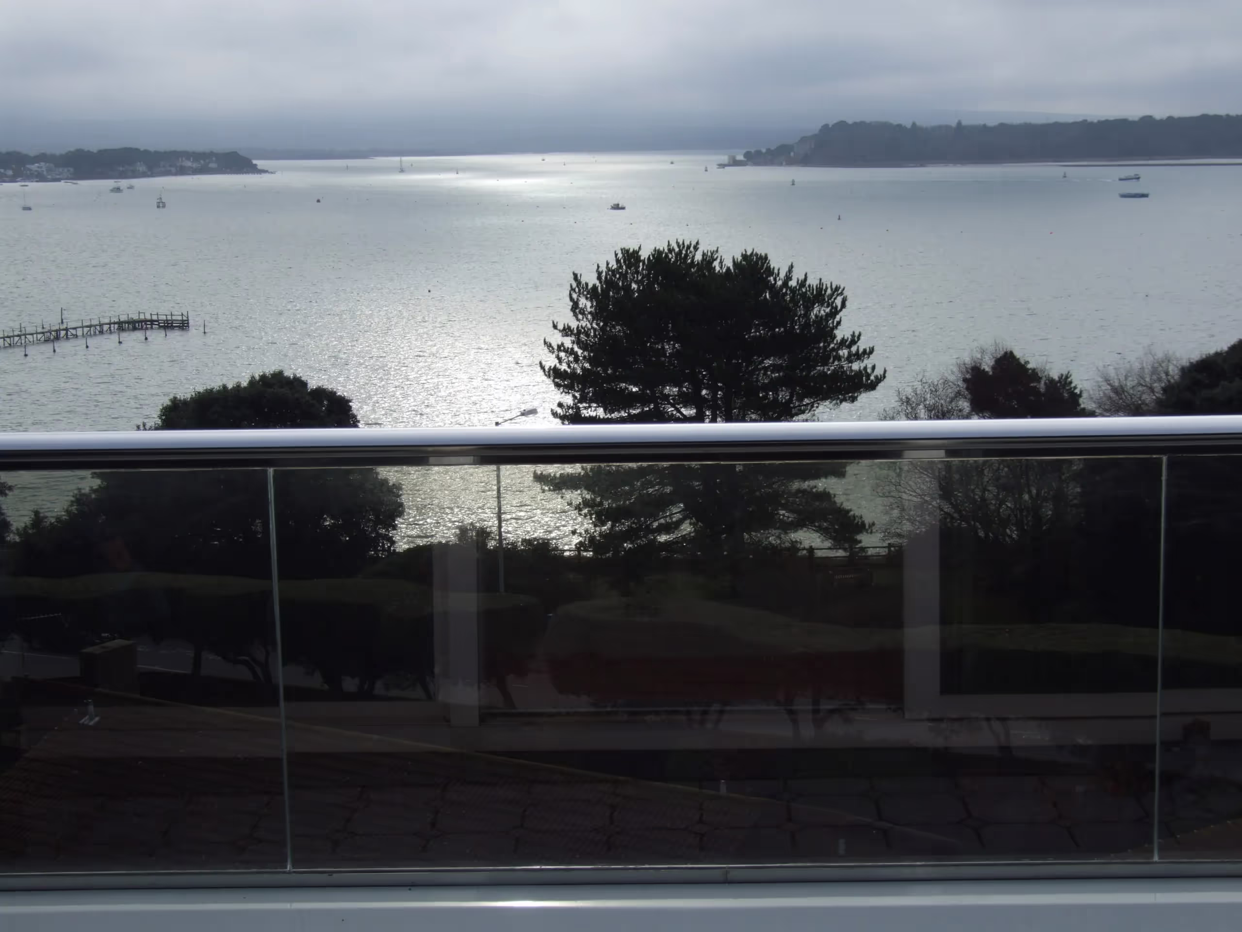 A glass balustrade with a stainless steel D-shaped rail overlooking Sandbank, Dorset, UK
