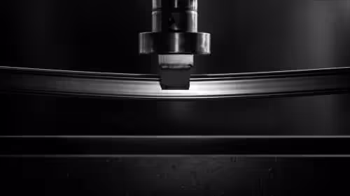 stainless steel mirror polished D-shaped tubing being stress tested under a hydraulic arm