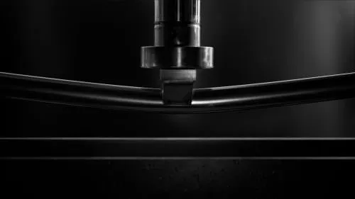 stainless steel mirror polished oval tubing being stress tested under a hydraulic arm