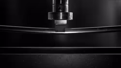 stainless steel mirror polished radius square tubing being stress tested under a hydraulic arm