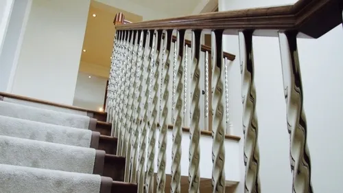 Staircase with stainless steel spindles made from twisted square tubing in a residential home