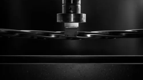 stainless steel mirror polished twisted square tubing being stress tested under a hydraulic arm
